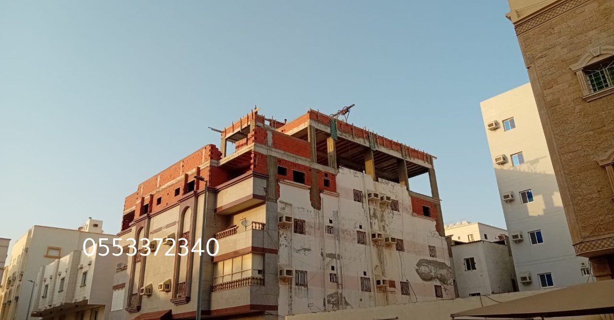 عمال بناء يرتدون معدات السلامة أثناء العمل في موقع البناء.